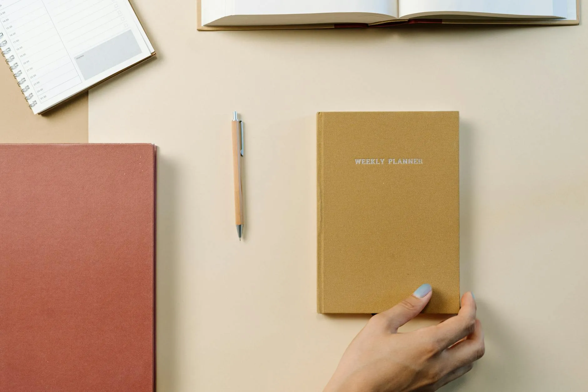 Top-down view of a desk with a weekly planner, notebook, and pen