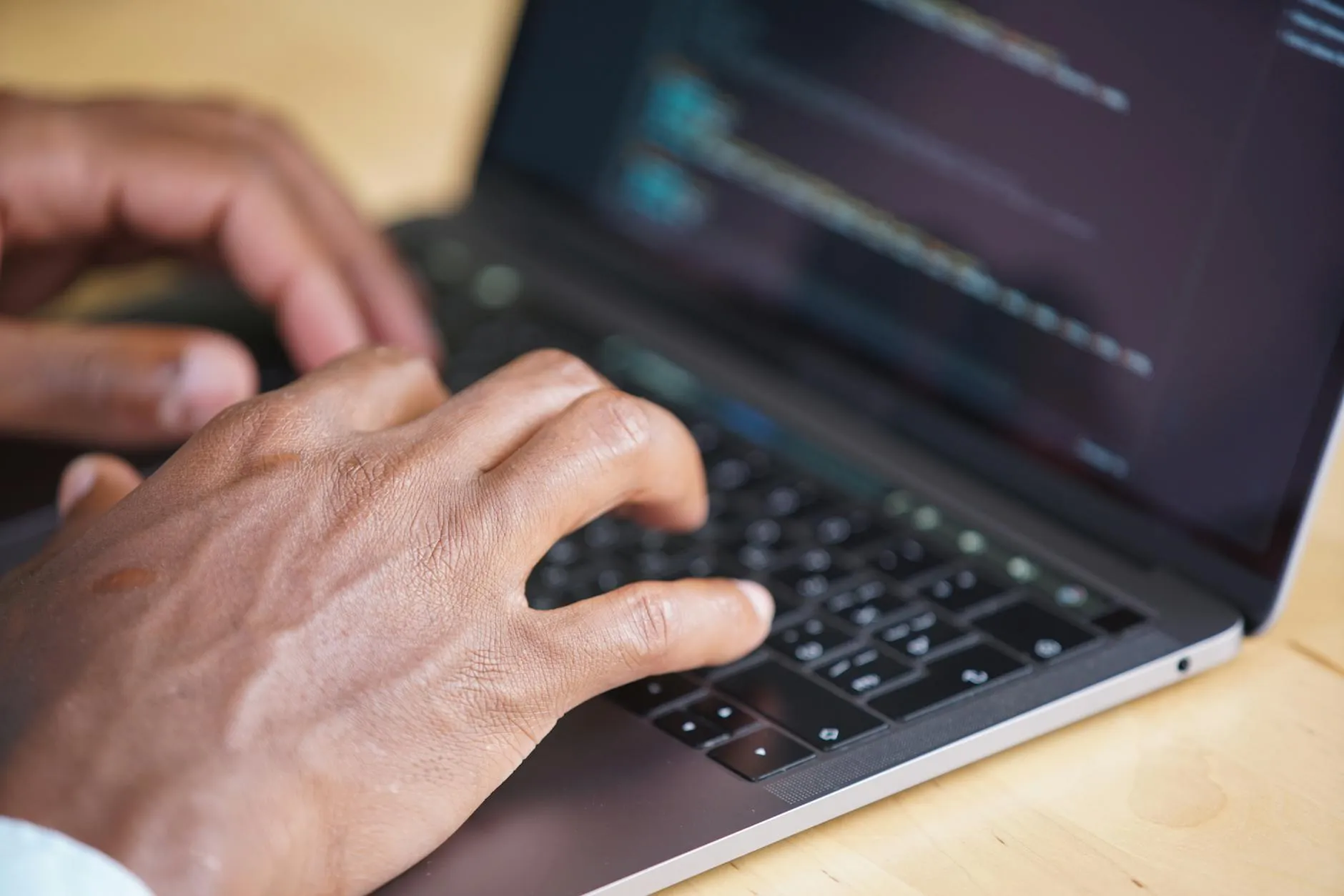 Hands typing on a laptop with code displayed on screen